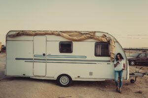 woman wearing white crew neck shirt leaning on rv trailer